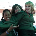 three high school girls embracing and smiling